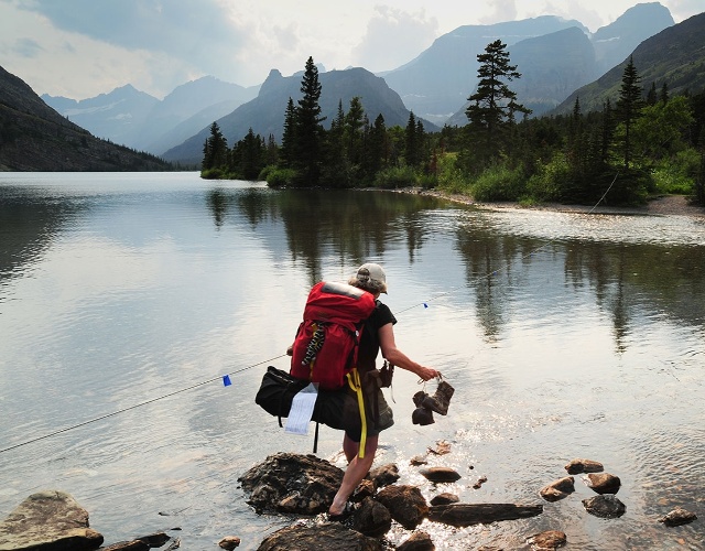 Hiker crossing outlet Cosley Lake, Glacier Park